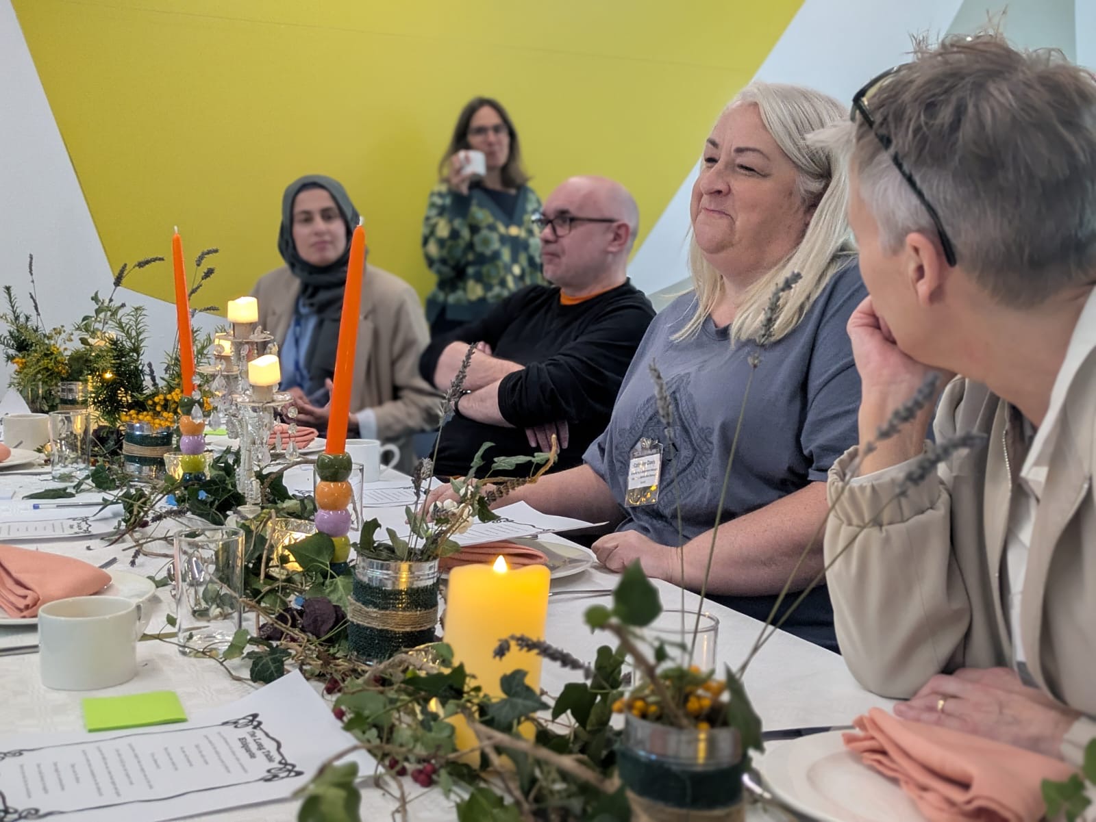 4 attendees at the Long Table and another attendee in the background observing