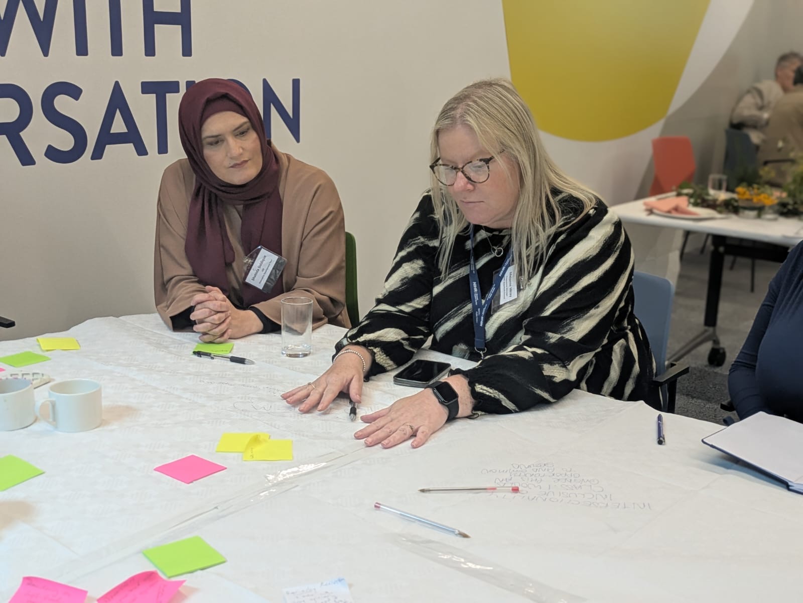 Two attendees looking at post-it notes working on the table exercise