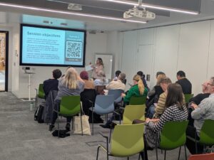 Attendees sitting in the crowd looking at the presentation to start the day