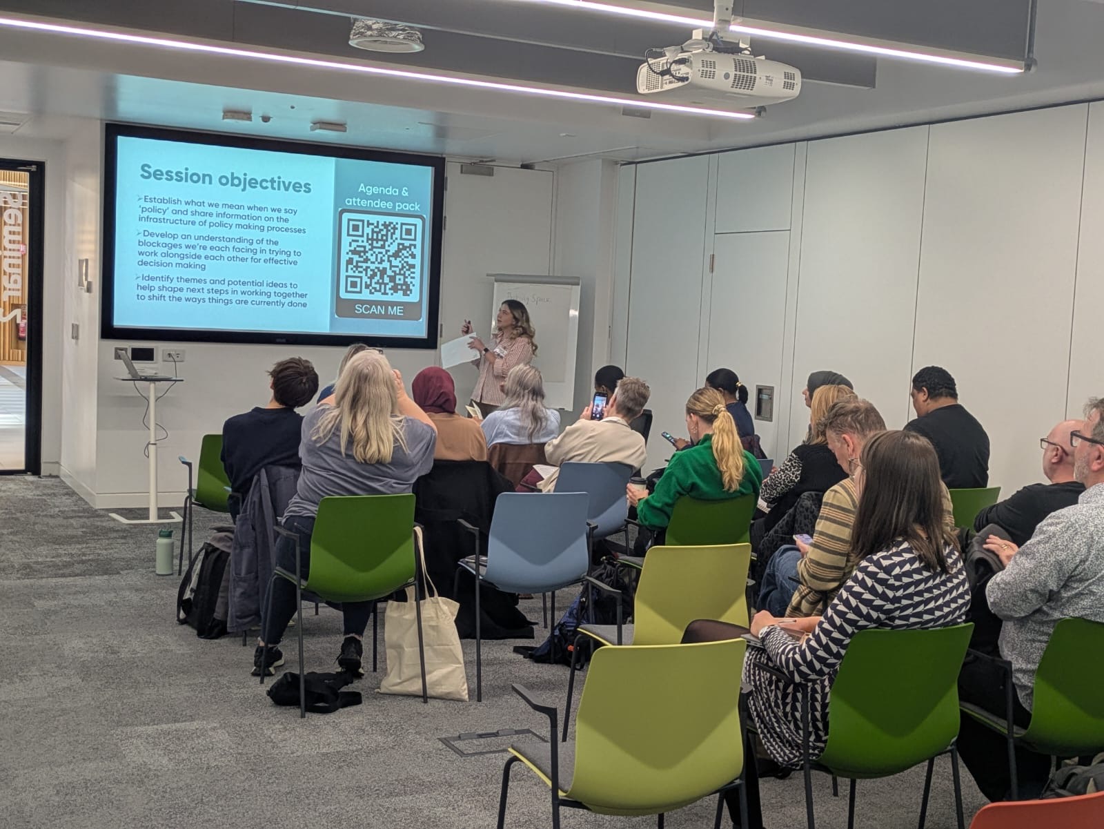 Attendees sitting in the crowd looking at the presentation to start the day