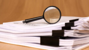 Stack of papers with a magnifying glass on top
