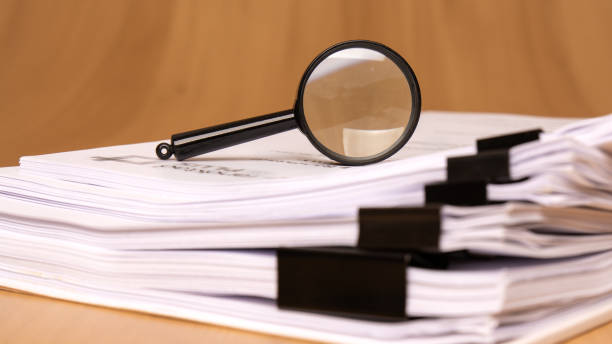 Stack of papers with a magnifying glass on top