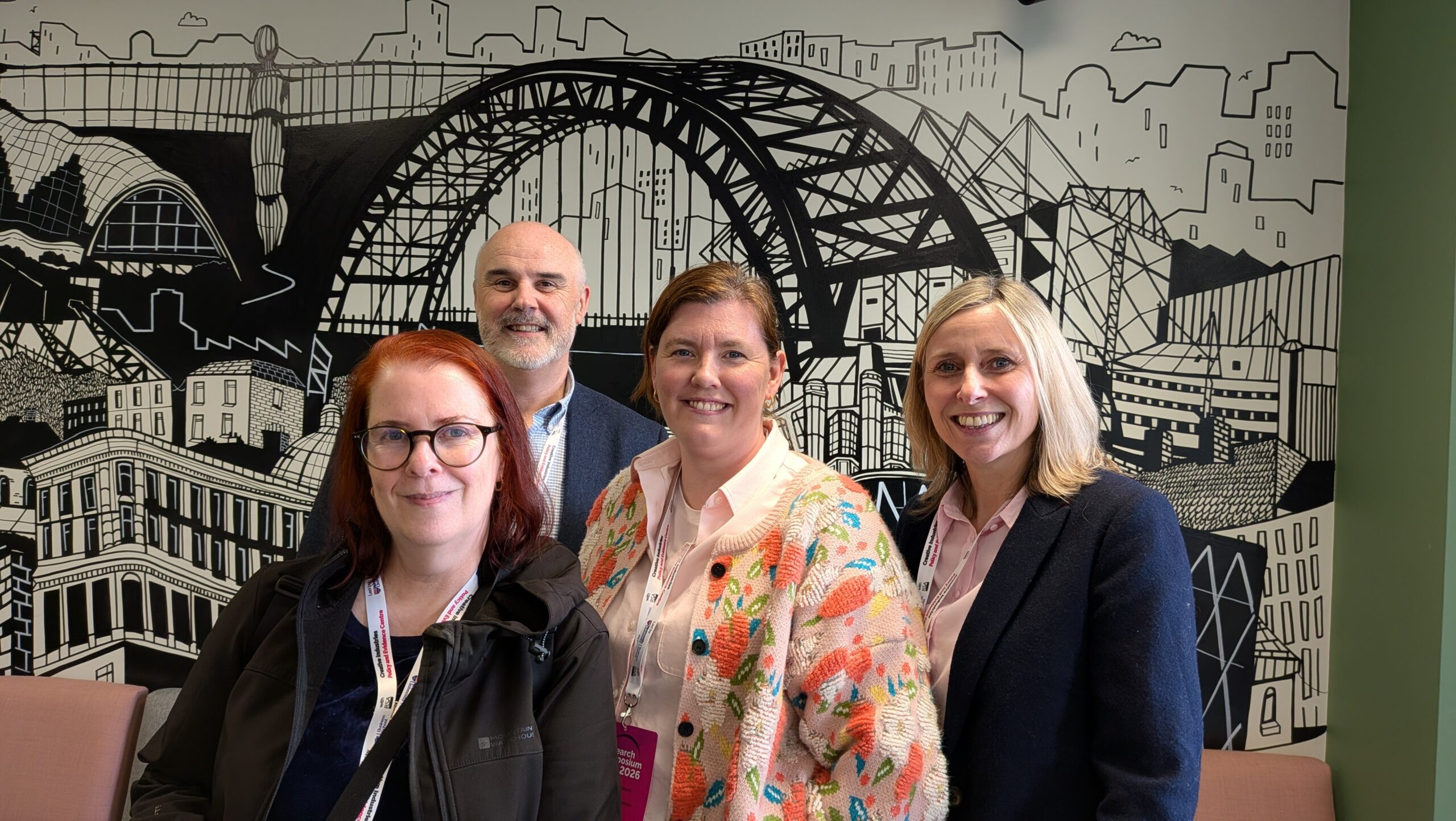 Group picture of Sam, Alex, Patsy and Nathan in front of an illustration of the Tyne Bridge in Newcastle