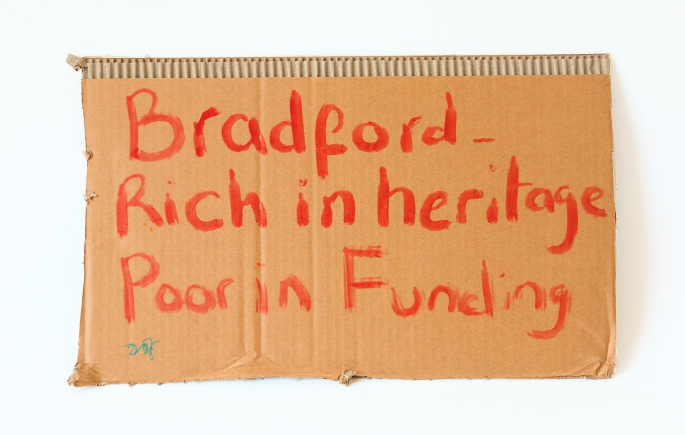 Cardboard painted with the words 'Bradford - rich in heritage, poor in funding'